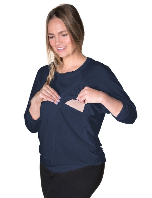 Woman wearing a navy blue nursing long sleeve shirt with a beige nursing pad underneath on a white background